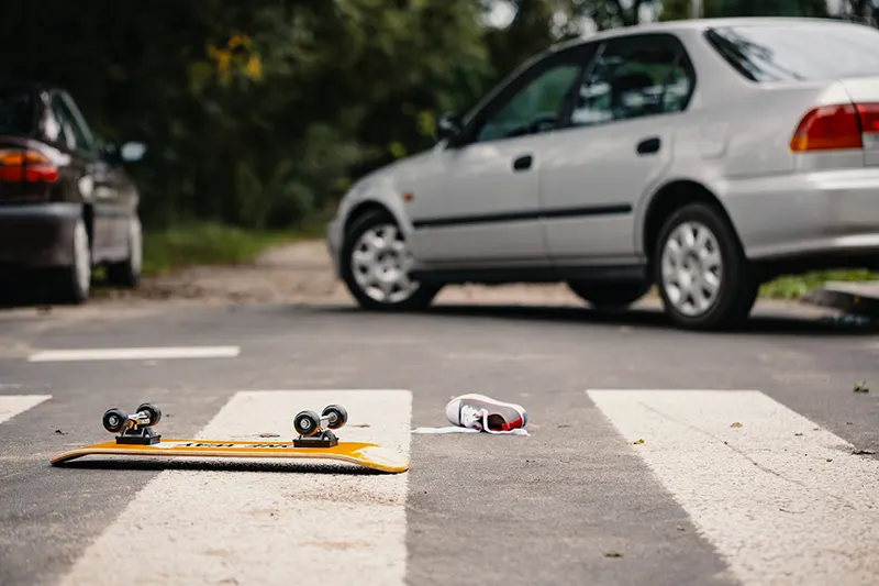 Skateboard and child's shoe on a pedestrian crossing after dangerous traffic incident