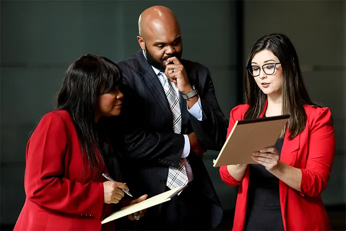 Three individuals inspecting a document and discussing auto accident tips