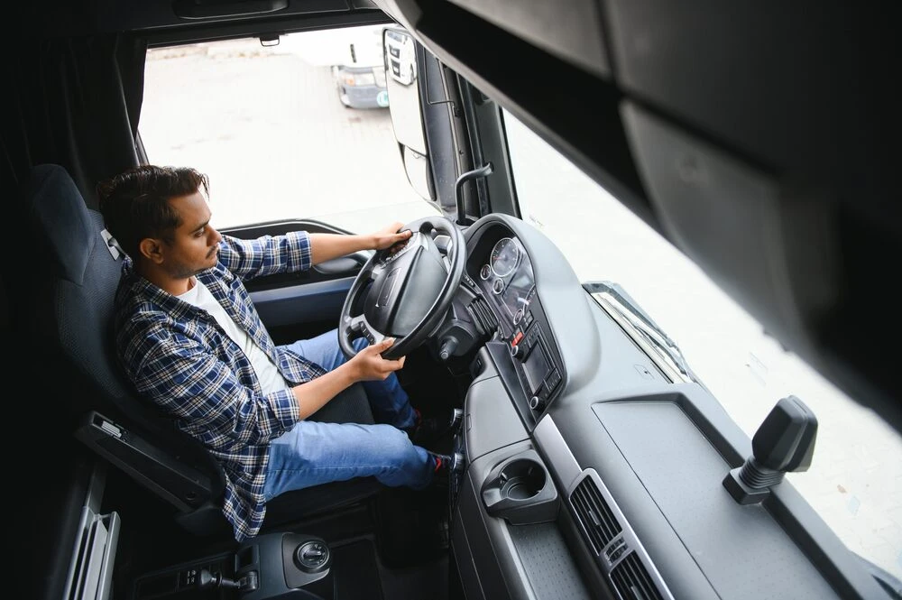 A young male truck driver sits behind the wheel.