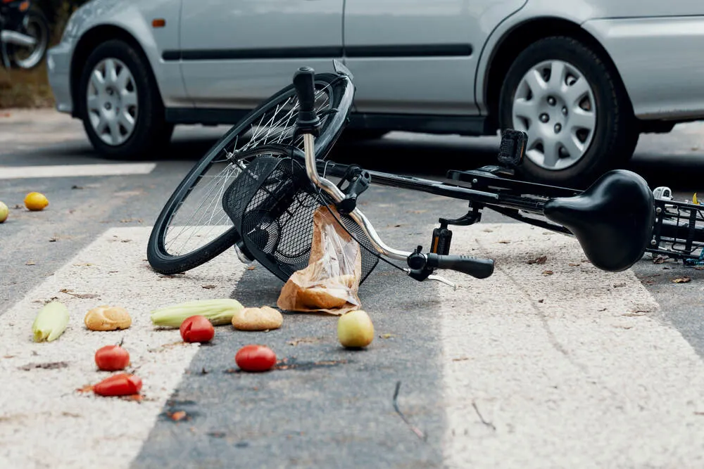 Groceries and broken bike on pedestrian crossing after collision with a car