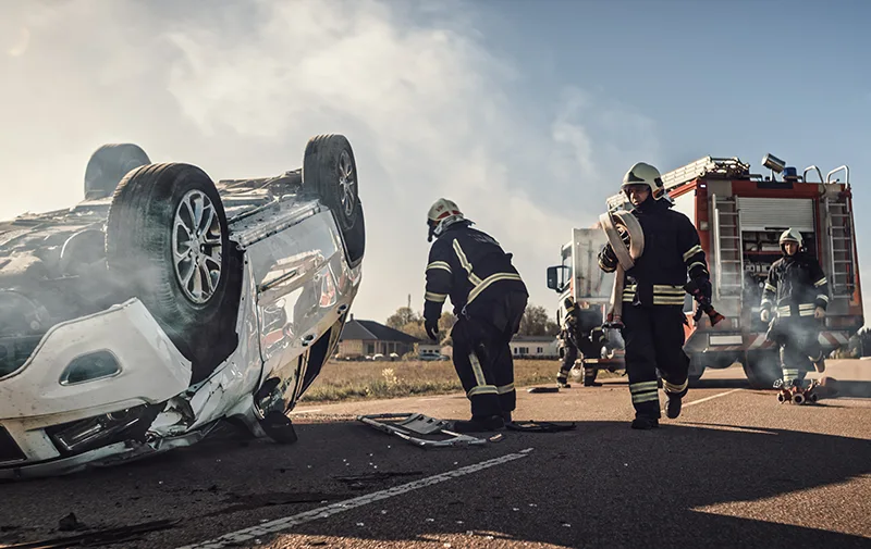 Rescue Team of Firefighters Arrive on the Car Crash Traffic Accident Scene on their Fire Engine. Firemen Grab their Tools, Equipment and Gear from Fire Truck, Rush to Help Injured, Trapped People