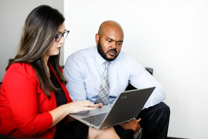 Woman and man sitting on a couch and looking at a laptop