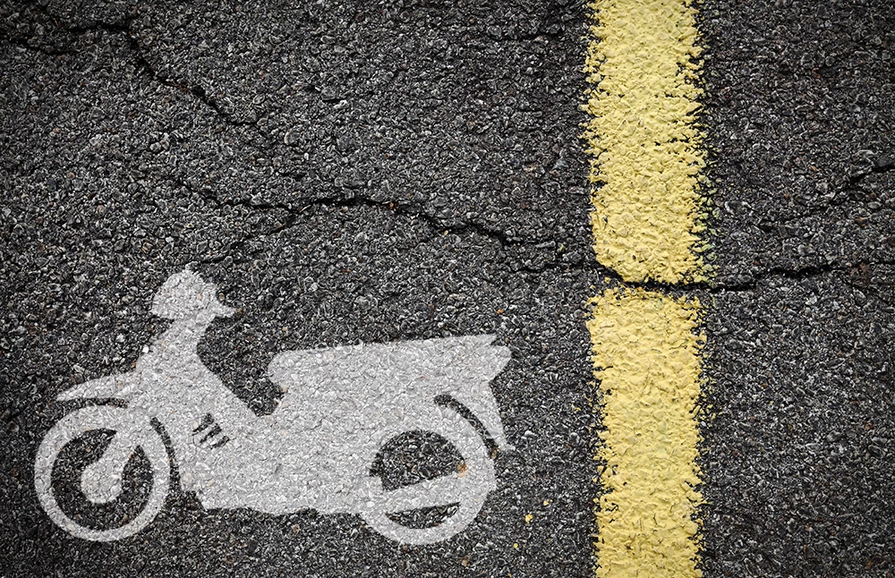 A motorcycle symbol painted on the surface of a tarmac road indicating a motorbike lane splitting