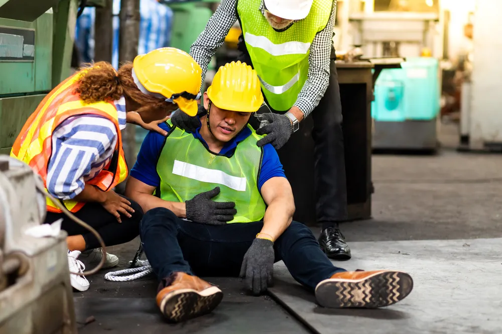 Engineering supervisor talking on walkie talkie communication while his coworker lying unconscious at industrial factory.