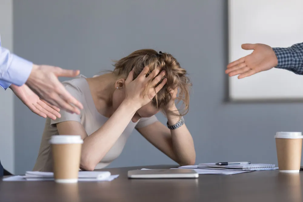 Stressed young businesswoman holding head in hands suffering from unfair gender discrimination