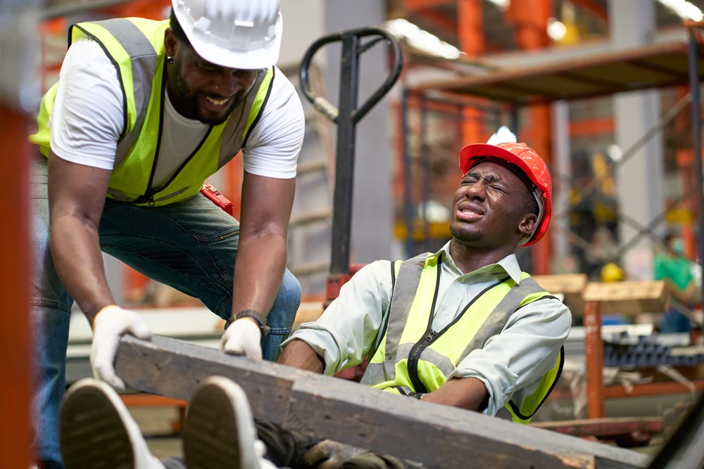 African American foreman help factory worker for accident trunk on leg in metal sheet manufacturing industrial factory